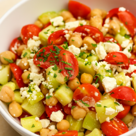 white bowl with chickpeas, tomatoes, cucumber, feta cheese, and parsley