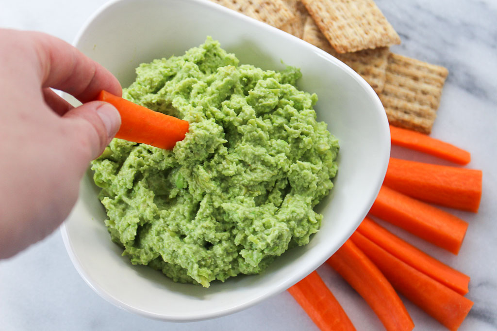 carrot being dunked into green dip