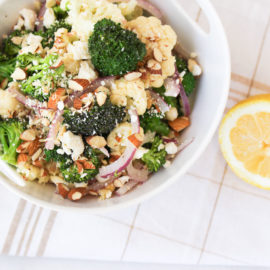 Broccoli cauliflower salad with red onions and almonds in a white bowl