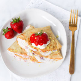 crepes with strawberry lemon ricotta filling in a white plate with gold fork
