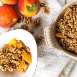 Peach walnut crisp in a baking dish and white bowl