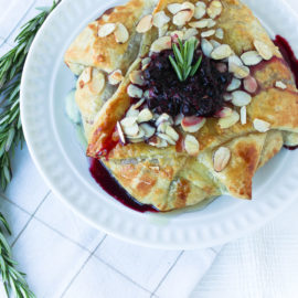 Wild Blueberry & Rosemary Stuffed Baked Brie on a white plate with rosemary