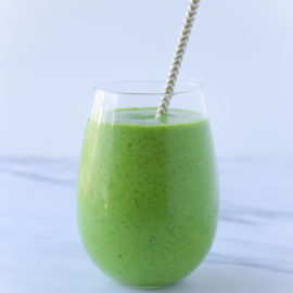 green smoothie in a glass with a gray straw