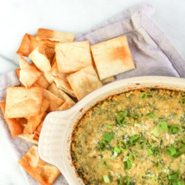 Cheesy Spinach Hummus Dip in a baking dish with pita chips