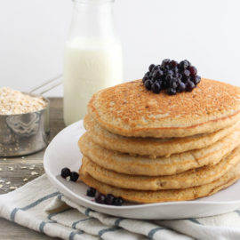 stack of oat flour pancakes on a white plate with blueberries