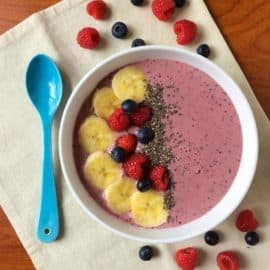 Very Berry Smoothie Bowl on a tan napkin with blue spoon