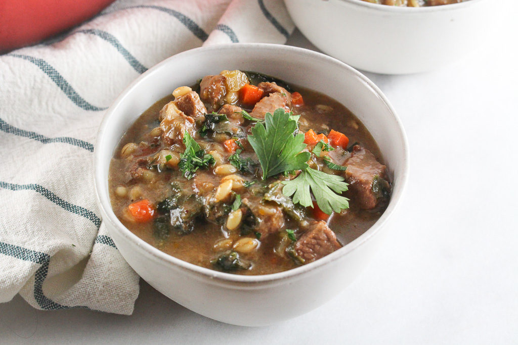 Beef & Barley Soup in a white bowl garnished with parsley