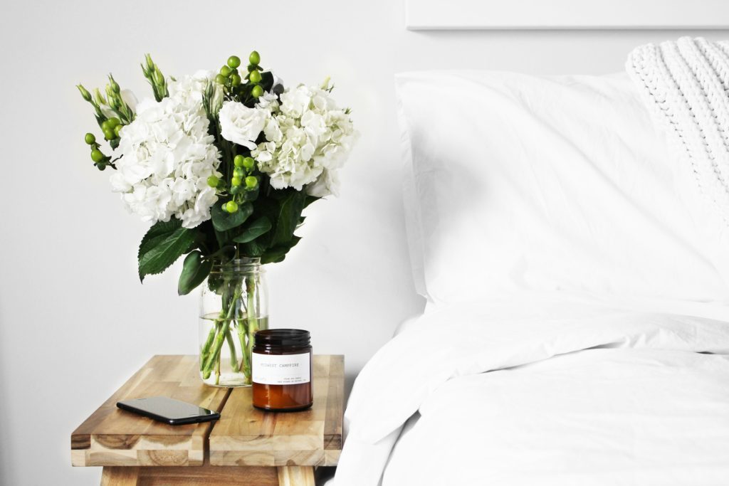 wooden bedside table with a floral arrangement and candle