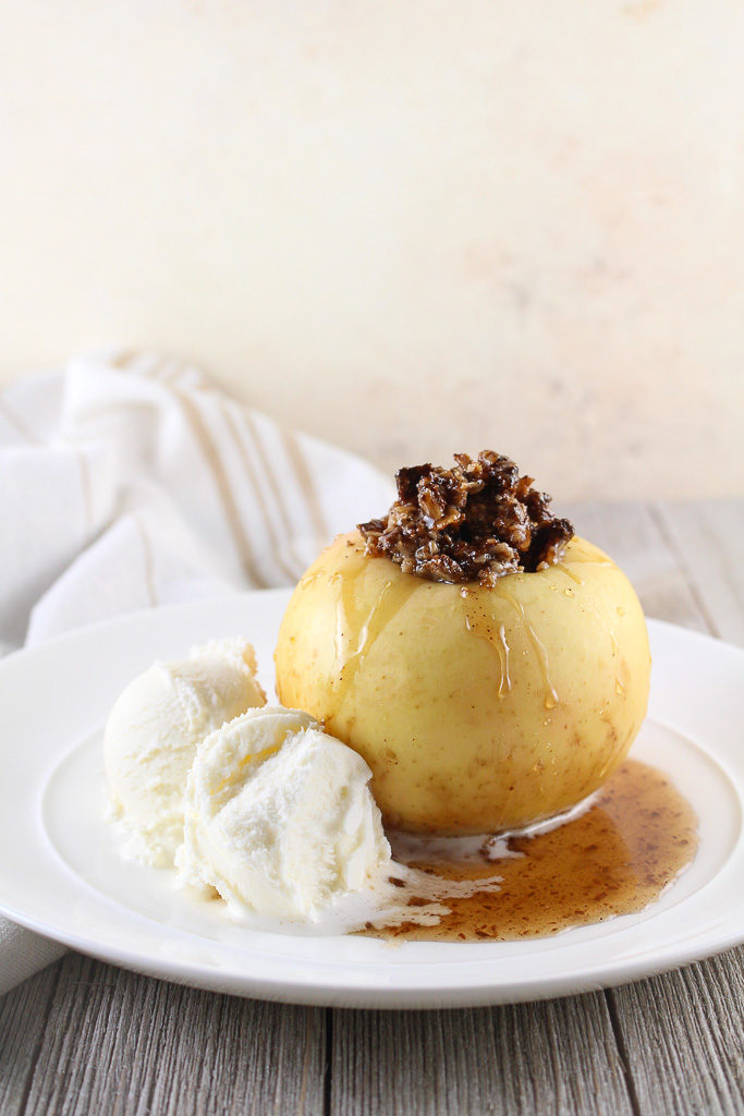 baked stuffed apple with vanilla ice cream on a white plate