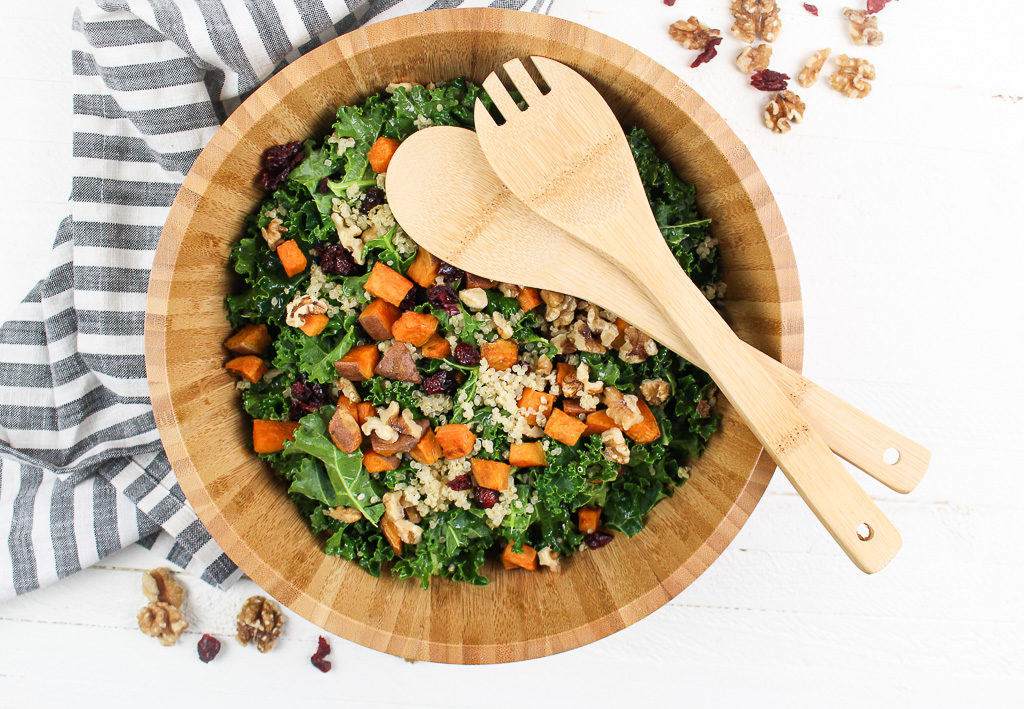 Roasted Sweet Potato Kale Salad in a wooden bowl with wooden serving utensils