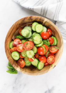 baby cucumbers with cherry tomatoes in a wooden bowl