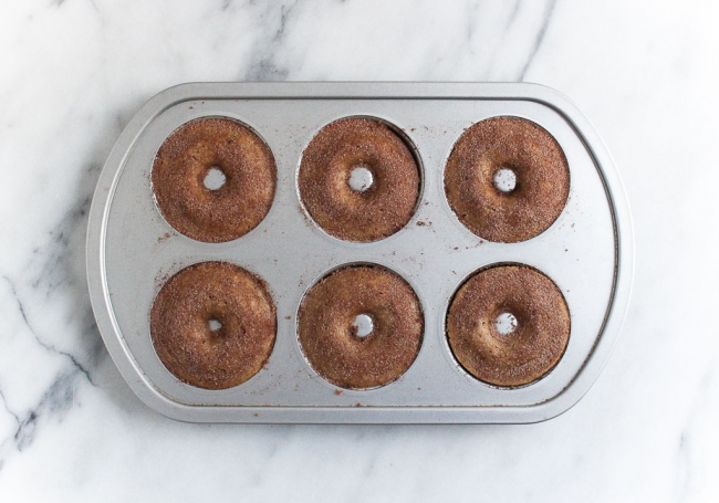 baked apple cider donuts in donut baking pan on a marble slab
