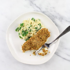 piece of pistachio crusted baked cod with orzo and spinach