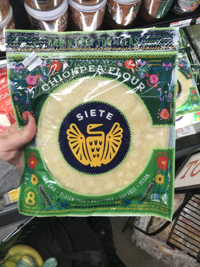 hand holding chickpea flour siete tortillas at the grocery store