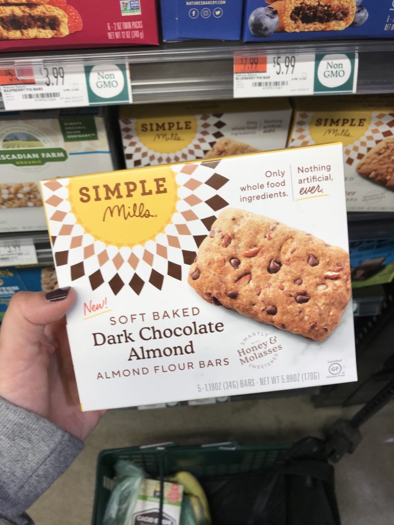 hand holding simple mills soft baked dark chocolate almond almond flour bars at the grocery store