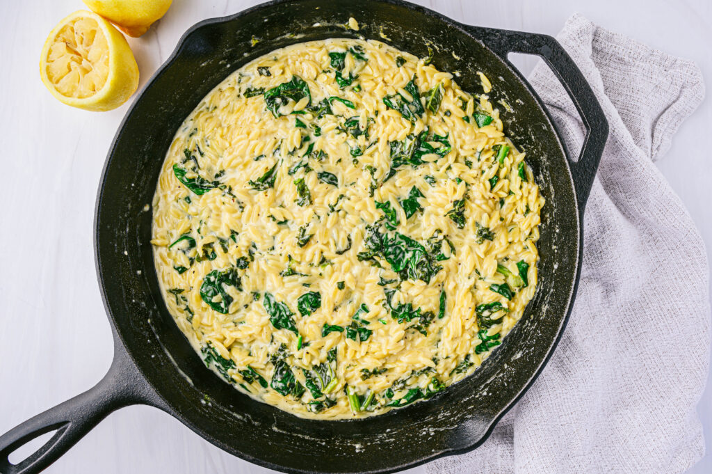 top view of creamy lemon and spinach orzo in a cast iron pan