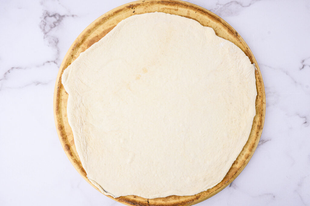 pizza dough spread out on a stone